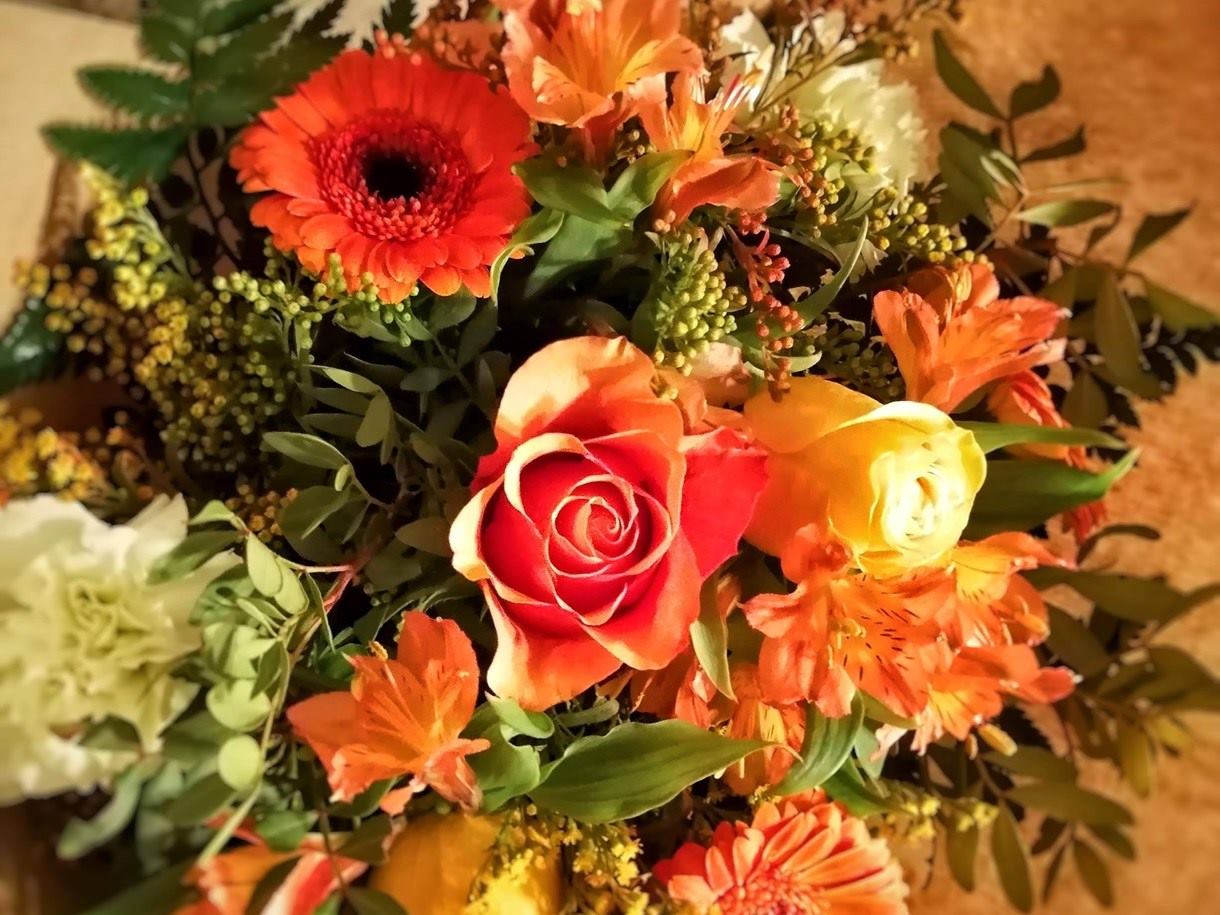 Cálido Bouquet compuesto por rosas, gerberas mini, alstromelia y solidago en colores naranjas y amarillos.