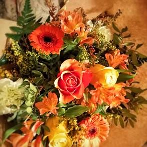 Cálido Bouquet compuesto por rosas, gerberas mini, alstromelia y solidago en colores naranjas y amarillos.